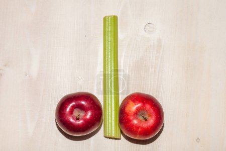 Téléchargez les photos : Pommes et céleri disposés sur un fond en bois - en image libre de droit
