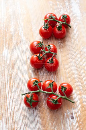 Téléchargez les photos : Tomate cerise sur fond bois clair - en image libre de droit
