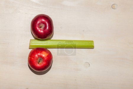 apples and celery arranged on light wooden background