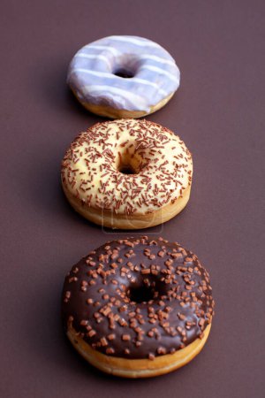 Photo for Three ring doughnuts isolated on brown background - Royalty Free Image