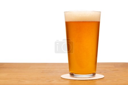 Foto de Full shaker pint glass of craft ale or beer on wooden table with white background - Imagen libre de derechos
