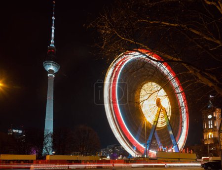Photo for Berlin, Germany - December 12, 2018: Spinning illuminated Ferris Wheel at Christkindlmarkt (Christmas market) in Central Berlin. Fernsehturm Television Tower is seen in background - Royalty Free Image