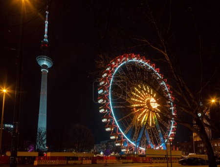Photo for Berlin, Germany - December 12, 2018: Illuminated Ferris Wheel at Christkindlmarkt (Christmas market) in Central Berlin. Fernsehturm Television Tower is seen in background - Royalty Free Image
