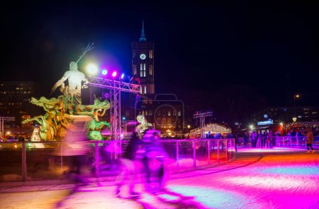 Photo for Berlin, Germany - December 12, 2018: People skating on ice rink at Christmas Market in Mitte at night. Skaters are blurred in motion. Red City Hall (Rotes Rathaus) is seen in background - Royalty Free Image