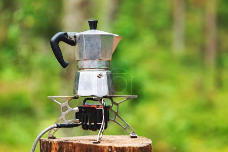 Photo for Brewing italian style coffee in aluminum moka pot on a portable stove during wild camping in a forest - Royalty Free Image