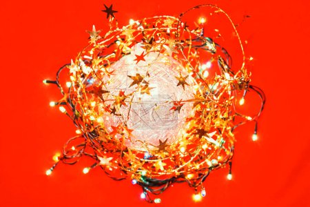 Photo for Round Christmas composition made of tinsel Christmas bauble and electric lights on red background - Royalty Free Image