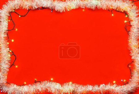Photo for Christmas frame made of tinsel and Christmas multicolored electric lights on red background - Royalty Free Image