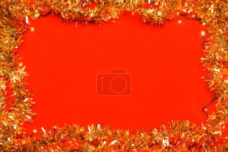 Photo for Christmas frame made of tinsel and Christmas electric lights on red background - Royalty Free Image