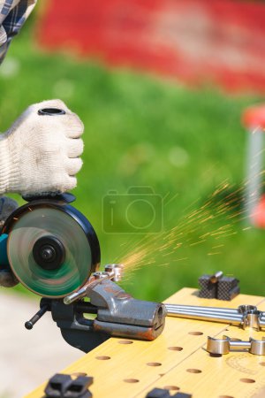 Photo for Person cuts metal rod with angle grinder outdoor - Royalty Free Image