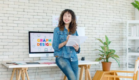 Photo for Asian professional successful young female creative graphic designer in casual fashionable denim jeans jacket standing smiling holding colors chart working in workspace in company office. - Royalty Free Image