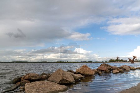 Felsbrocken im Wasser des Wolderwijd mit dem Denkmal für alliierte Flieger bei Harderwijk, Niederlande im Hintergrund