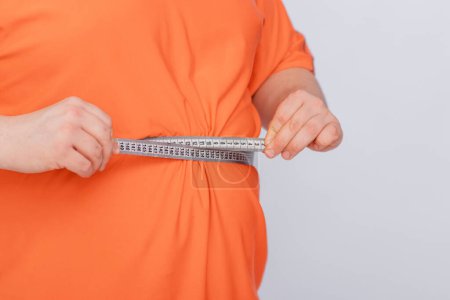 Foto de Primer plano de un hombre midiendo su vientre gordo con cinta métrica aislada sobre fondo blanco - Imagen libre de derechos