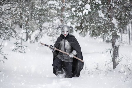 A medieval fantasy warrior in a horned helmet, a steel breastplate and chain mail with a two-handed ax in his hands, walks through snowdrifts in a winter forest. puzzle 703322670