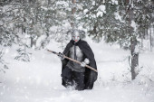 A medieval fantasy warrior in a horned helmet, a steel breastplate and chain mail with a two-handed ax in his hands, walks through snowdrifts in a winter forest. Stickers #703322670