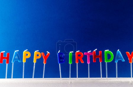 Muchas velas de colores con texto Feliz cumpleaños