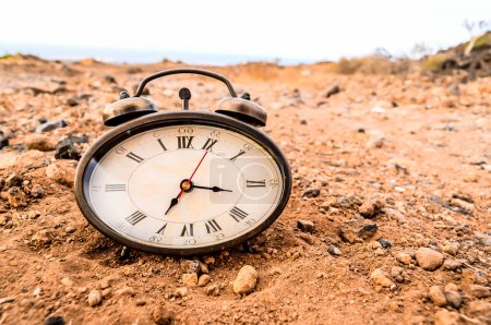 Die klassische analoge Uhr im Sand in der Felsenwüste