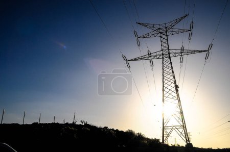 Pilón de línea de energía eléctrica sobre una puesta de sol de color