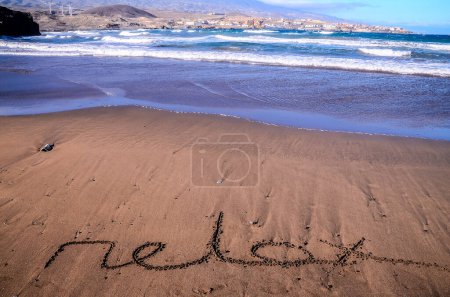 Palabra escrita en la arena de una playa tropical