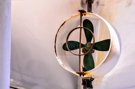 A fan is hanging from the ceiling with a green leaf on it