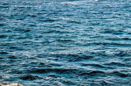 Das Meer ist ruhig und blau. Das Wasser steht still und die Wellen sind klein. Der Himmel ist klar und die Sonne scheint