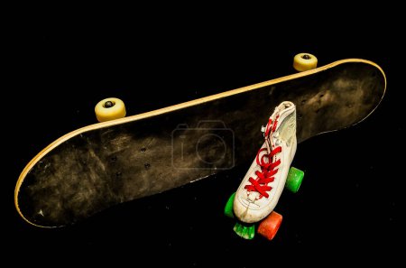 A skateboard and a pair of roller skates are placed next to each other