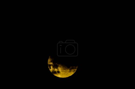 A large yellow moon is in the sky. The moon is the main focus of the image