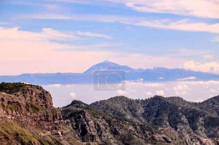 A mountain range with a large mountain in the background. The sky is clear and blue with a few clouds, real image