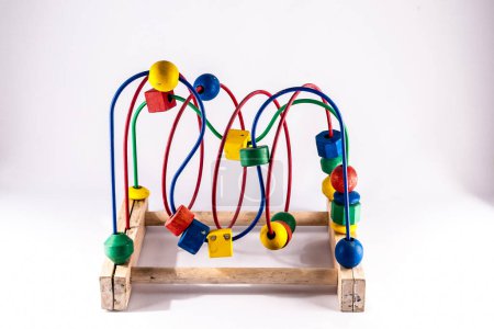 A wooden toy with colorful balls and a red and yellow piece. The toy is a puzzle and is placed on a wooden base