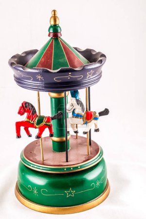 A green carousel with three horses on it. The horses are red, white and blue