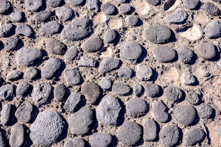 A close up of a rocky surface with many small rocks scattered about. The image has a rugged, natural feel to it, with the rocks appearing to be weathered and worn. Scene is one of ruggedness