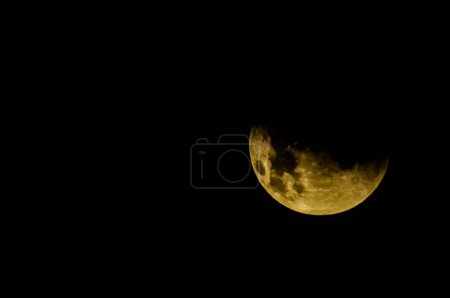 Ein großer gelber Mond steht am Himmel über einem schwarzen Hintergrund. Der Mond steht im Mittelpunkt des Bildes und leuchtet hell. Der Kontrast zwischen dem leuchtend gelben Mond