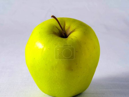 Une pomme verte avec une tige sur le dessus. La pomme sur fond blanc. La pomme est mûre et prête à manger