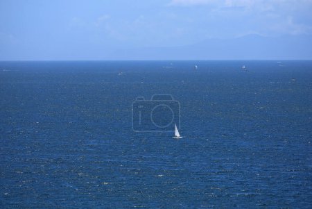 Blue sky, blue sea and white sailing dinghy