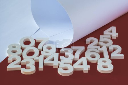 Volumetrische weiße Plastikzahlen und Papierbögen auf rotem Hintergrund.
