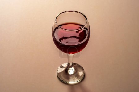 Glass of red wine on a light red background.