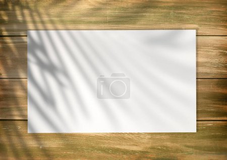 Leere weiße Liste auf einem hölzernen leeren Hintergrund im alten Stil mit Plamblattschatten darauf. Leere Papier-Attrappe, Draufsicht