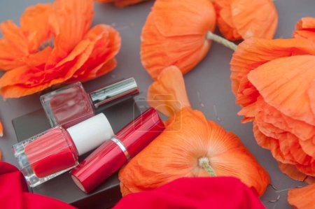 Foto de Cosméticos de color rojo y manojo de amapolas, esmalte de uñas rojo y botellas de lápiz labial - Imagen libre de derechos
