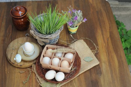 Téléchargez les photos : Œufs de poulet crus biologiques dans une boîte à œufs naturelle sur une table en bois ancienne, vue sur le dessus - en image libre de droit