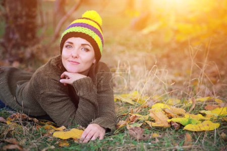 Foto de Retrato de mujer sonriente vestida con gorro sombrero con pompón, al aire libre en el parque de otoño - Imagen libre de derechos