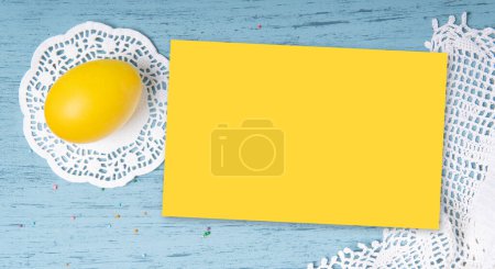 Foto de Yellow empty paper list mockup on Easter background with yellow colored egg and knitted napkins - Imagen libre de derechos
