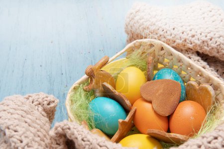Foto de Basket with Easter colored eggs and holiday homemade cookies - Imagen libre de derechos