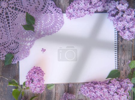Foto de Cuaderno vacío lista vista superior maqueta con flores lila, servilleta de ganchillo y sombra - Imagen libre de derechos