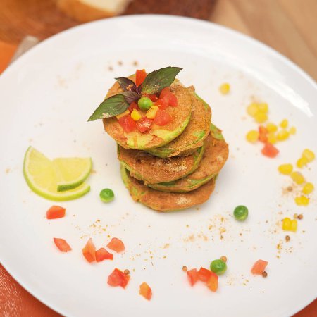 Foto de Buñuelos de verduras de panqueques de calabacín servidos en un plato en la cafetería al aire libre, vista superior - Imagen libre de derechos