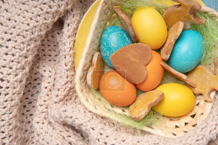 Photo for Easter background with colored eggs and holiday Easter cookies on a knitted cloth - Royalty Free Image