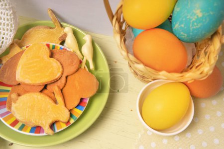 Foto de Lista blanca vacía sobre fondo de Pascua con huevos de colores y galletas caseras de vacaciones - Imagen libre de derechos