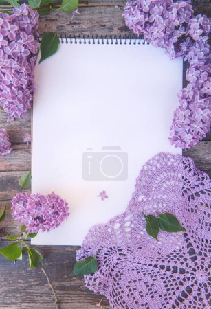 Foto de Cuaderno vacío lista vista superior maqueta con flores lila y servilleta de ganchillo, vertical - Imagen libre de derechos