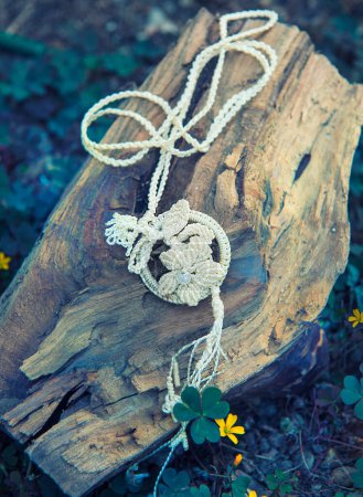 Téléchargez les photos : Collier tricoté artisanal fait main sur trèfle et fleurs en toile de fond - en image libre de droit