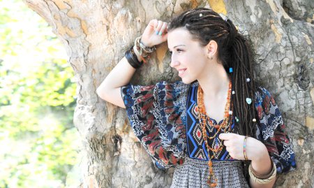 Foto de Retrato de perfil de mujer joven con peinado dreadlocks posando en un soleado parque al aire libre - Imagen libre de derechos