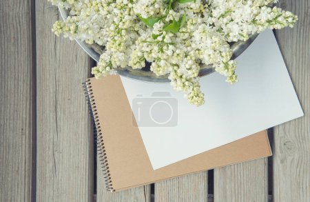 Téléchargez les photos : Carte en papier blanc avec fleurs lilas blanches et fond en bois - en image libre de droit