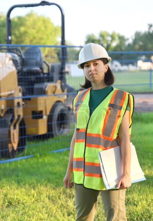 Photo for Outdoor builder portrait, construction woman worker standing near workplace with blueprints - Royalty Free Image